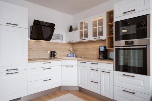 a kitchen with white cabinets and black appliances at Hauptstraße 26e Deck 9 in Timmendorfer Strand