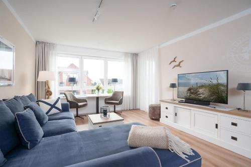 a living room with a blue couch and a tv at Hauptstraße 26e Deck 9 in Timmendorfer Strand
