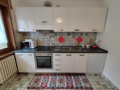 a kitchen with white cabinets and a sink at Villa Salagona in Laggio