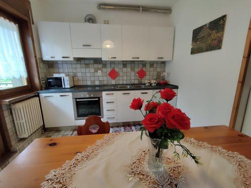 a vase with red roses on a table in a kitchen at Villa Salagona in Laggio