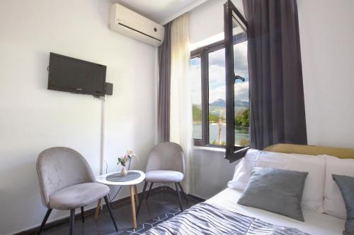 a bedroom with a bed and two chairs and a window at Apartments MaXhit in Tivat