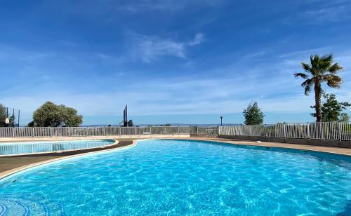 une grande piscine bleue avec une clôture et un palmier dans l'établissement Coquet logement tout confort avec piscine, à Béziers