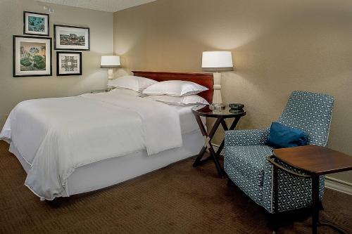 a bedroom with a bed and a table and a chair at Sheraton Westport Lakeside Chalet in Maryland Heights