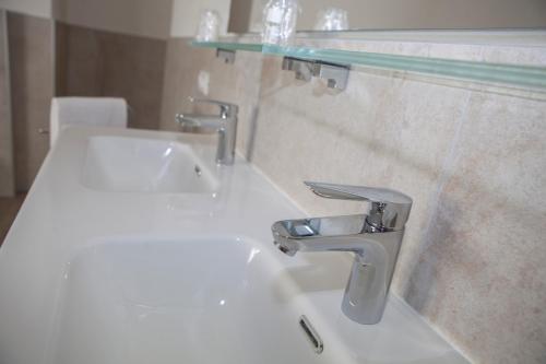 a bathroom with a white sink and a glass shelf at Hotel Benacus Torri del Benaco in Torri del Benaco