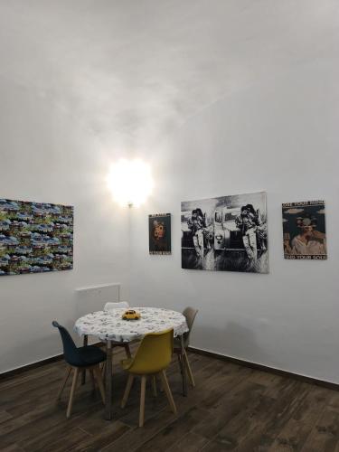 a table and chairs in a room with paintings on the wall at Appia Apartment - Camera Fiorellino in Santa Maria a Vico