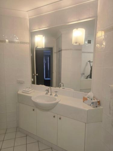 a white bathroom with a sink and a mirror at Bayview Anchorage in Gold Coast