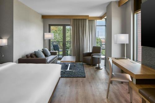a hotel room with a desk and a living room at AC Hotel Savannah Historic District in Savannah