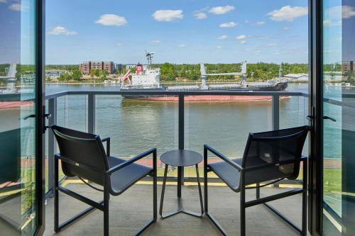 two chairs and a table on a balcony with a boat at AC Hotel Savannah Historic District in Savannah