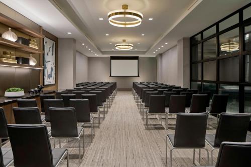 a conference room with rows of chairs and a screen at AC Hotel Savannah Historic District in Savannah