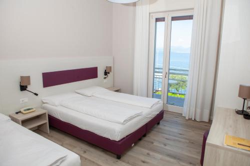 a hotel room with two beds and a balcony at Hotel Benacus Torri del Benaco in Torri del Benaco