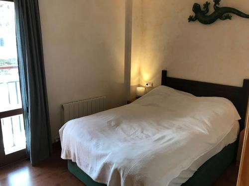 a white bed in a bedroom with a window at Benasque Valley Apartment in Bisaurri
