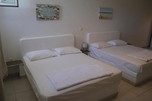 two beds in a room with white walls at Ateni House Garden in Agios Petros