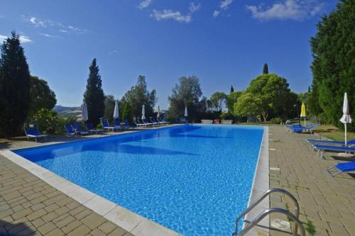 ein großer Swimmingpool mit blauen Stühlen und Sonnenschirmen in der Unterkunft Leonina Country House by Francigena Apartments in Casetta