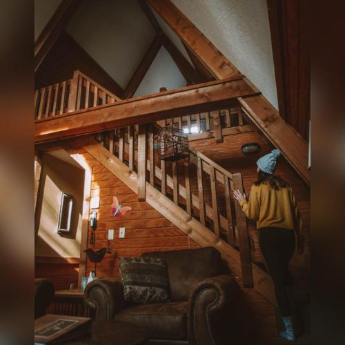 a woman walking up the stairs of a cabin at A-Frame #06 - by The Chalets in Logan