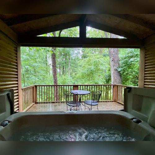 a tub on a deck with a table and chairs at A-Frame #07 - by The Chalets in Logan