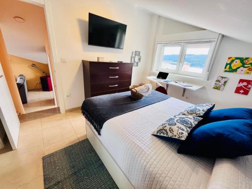 a bedroom with a bed with blue pillows and a television at Fogar das Pupieiriñas in Corcubión