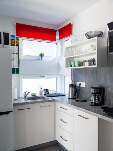 a kitchen with white cabinets and red accents at Słoneczne Domki in Krościenko