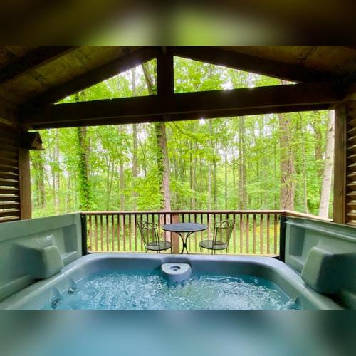 a hot tub on a screened in porch with a table at A-Frame #11 - by The Chalets in Logan