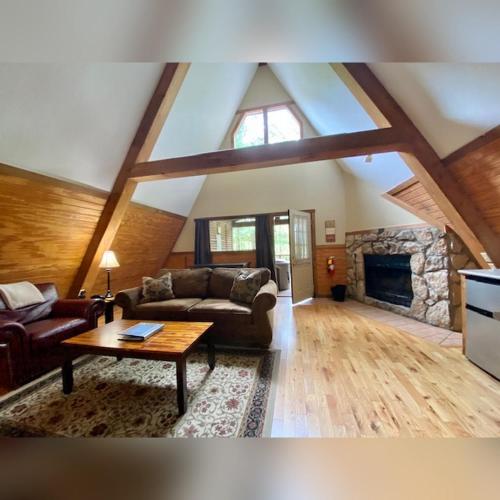 a living room with couches and a stone fireplace at A-Frame #11 - by The Chalets in Logan