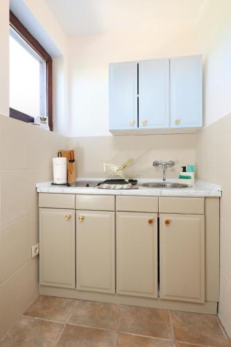 a kitchen with white cabinets and a sink at Apartments Kala in Jadranovo
