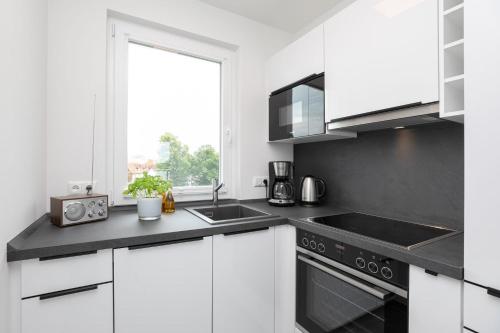 a kitchen with white cabinets and a sink and a window at Brenkenhagener Weg 4 Wohnung 7 in Grömitz