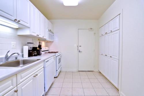 a white kitchen with white cabinets and a sink at Stylish Stay Near Metro and Downtown Charm in Arlington