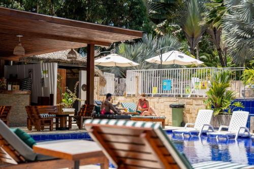 two people sitting by a pool with chairs and umbrellas at Hotel Villa Camila in La Pintada