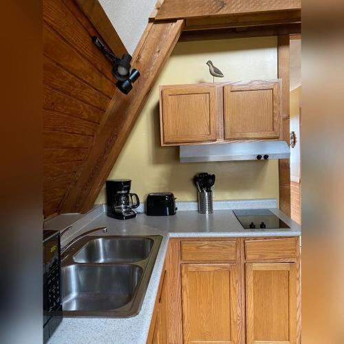 a kitchen with a sink and wooden cabinets at A-Frame #17 - by The Chalets in Logan