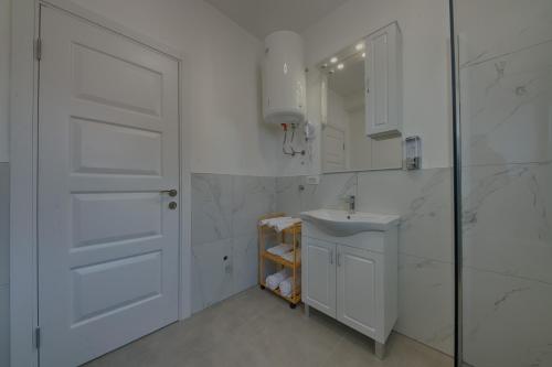 a white bathroom with a sink and a mirror at ARA Lux Apartments in Utjeha