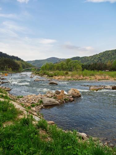 a river with rocks and a bridge in the background at Słoneczne Domki in Krościenko