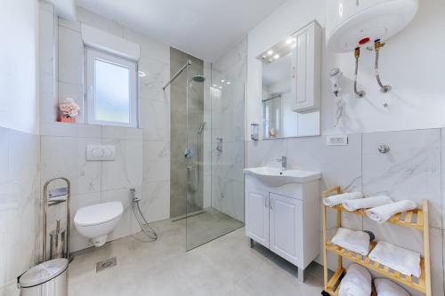 a white bathroom with a sink and a shower at ARA Lux Apartments in Utjeha