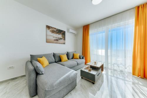 a living room with a gray couch and orange curtains at ARA Lux Apartments in Utjeha