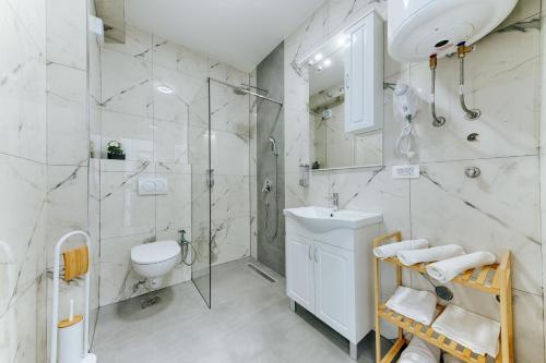 a white bathroom with a shower and a sink at ARA Lux Apartments in Utjeha