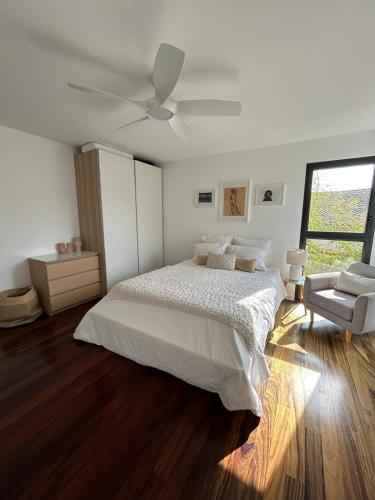 une chambre blanche avec un lit et un ventilateur de plafond dans l'établissement Maison d'architecte avec piscine au centre-ville, à Marseillan