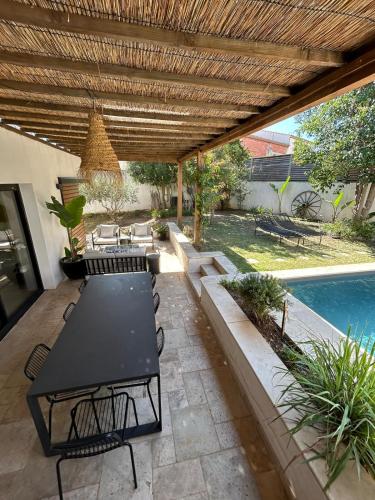 un patio avec une table et des chaises et une piscine dans l'établissement Maison d'architecte avec piscine au centre-ville, à Marseillan
