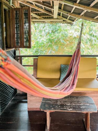 a hammock is hanging in a room with a bench at Nubá Boutique Hostel Palomino in Palomino