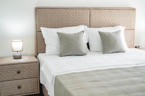 a bed with white pillows and a lamp on a night stand at ARA Lux Apartments in Utjeha