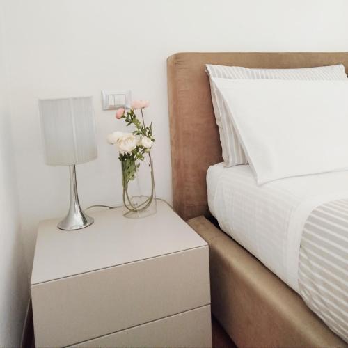 a bed with a nightstand with a vase of flowers on it at Carneval and Tuscany in Viareggio