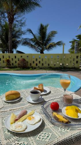 a table with plates of food and a glass of juice at Hospedagem Clima Mar in Valença