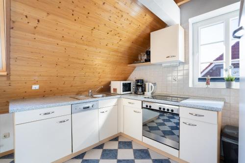 eine Küche mit weißen Schränken und einer Holzdecke in der Unterkunft Appartementhausanlage Tiemann Bernstein in Kellenhusen