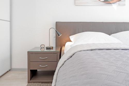 a bedroom with a bed and a nightstand with a lamp at Strandvilla Augustusbad Ostseeparadies in Scharbeutz