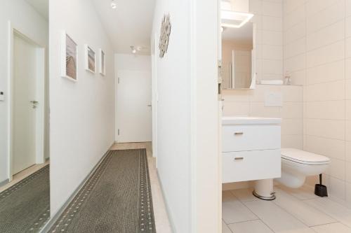 a white bathroom with a toilet and a sink at Strandvilla Augustusbad Ostseeparadies in Scharbeutz