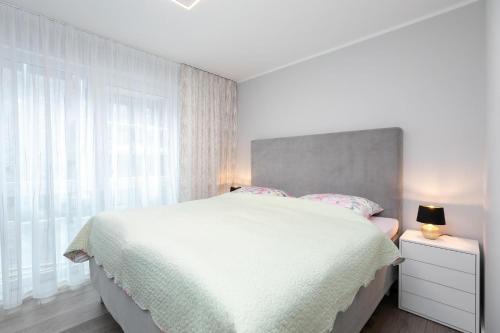 a white bedroom with a large bed and a window at Lucia in Scharbeutz