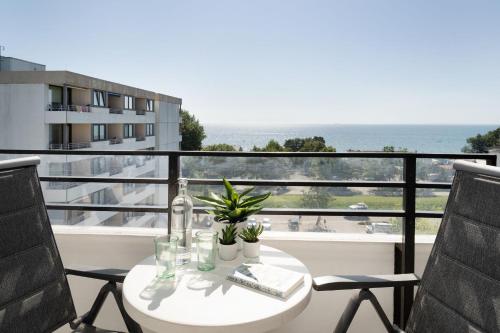 ein Tisch und Stühle auf einem Balkon mit Blick auf das Meer in der Unterkunft Haus Meeresblick Wohnung 79 in Kellenhusen