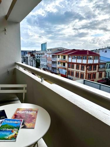 ein Balkon mit Tisch und Blick auf eine Stadt in der Unterkunft Azur Studio in Fort-de-France