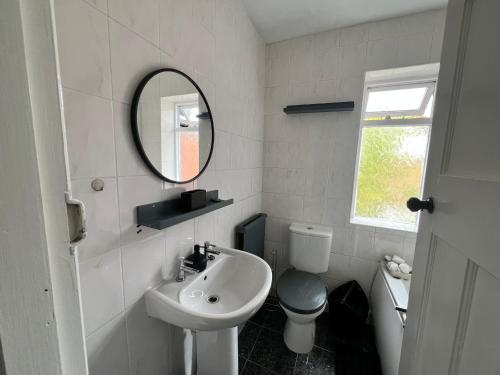 a bathroom with a sink and a toilet and a mirror at Spacious House Close to Central Manchester With Free Parking in Manchester