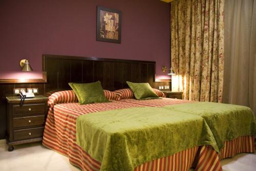 um quarto com uma cama grande e lençóis verdes em Hotel Las Acacias em Puente Genil