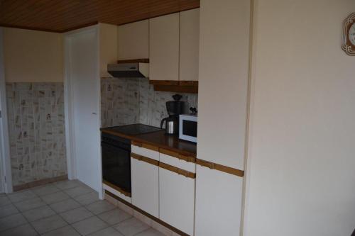 a kitchen with white cabinets and a microwave at Het Margrietje in Merkem