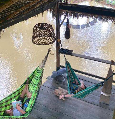 two people laying in hammocks next to a body of water at Amazon jungle cabin - satorinatural in Puerto Nariño
