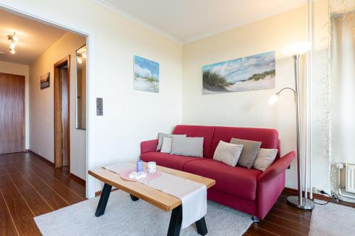 a living room with a red couch and a table at Meerblick mit Wohlfühlfaktor in Staberdorf